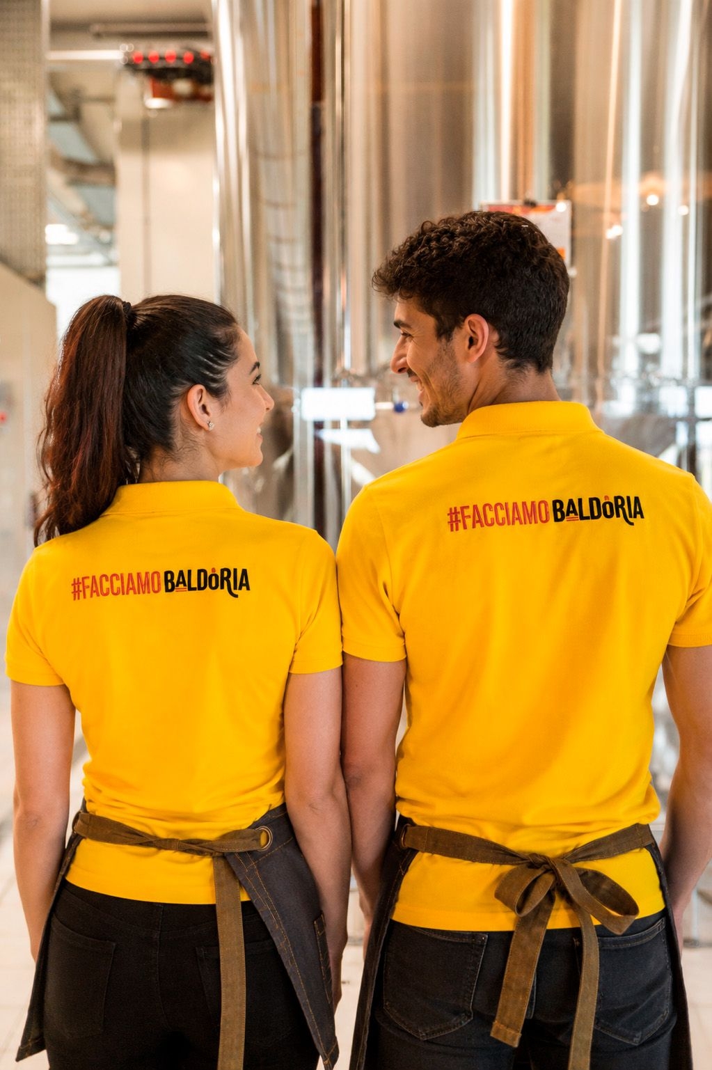 Divise coordinate del personale Baldoria con polo gialle e scritta personalizzata sulla schiena
