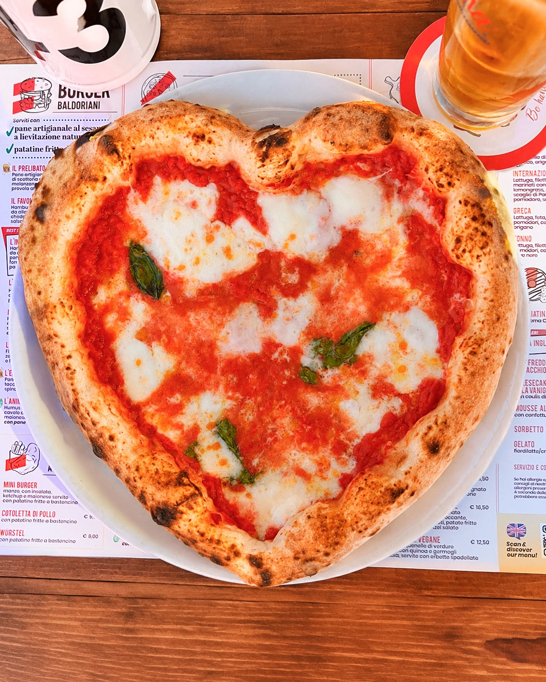 Pizza a forma di cuore servita sul materiale coordinato del locale Baldoria