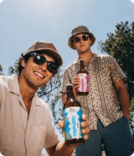 Due ragazzi mostrano bottiglie di birra artigianale Beha all’aperto