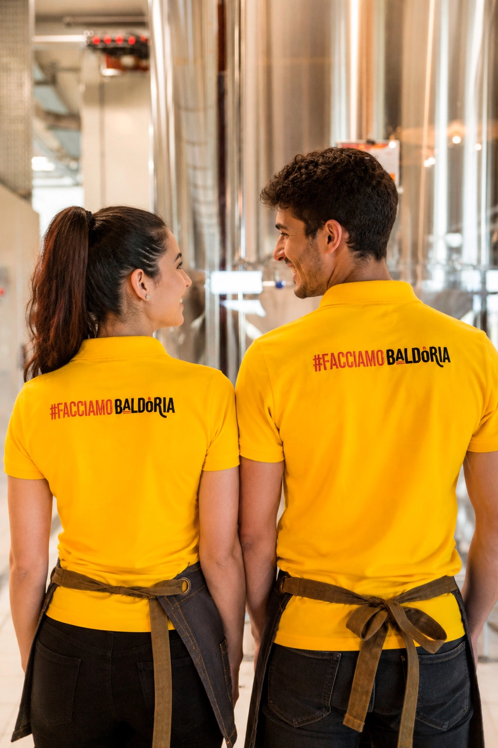 Due membri dello staff Baldoria con polo gialla nella sala del birrificio